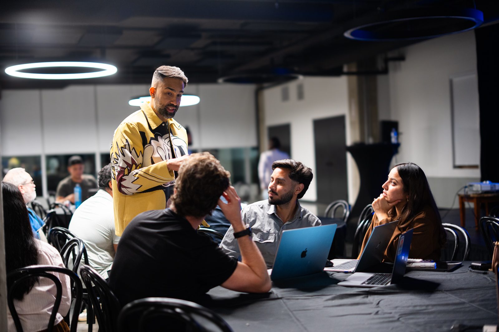 Nav at a table with three attendees, working through a build on their laptops